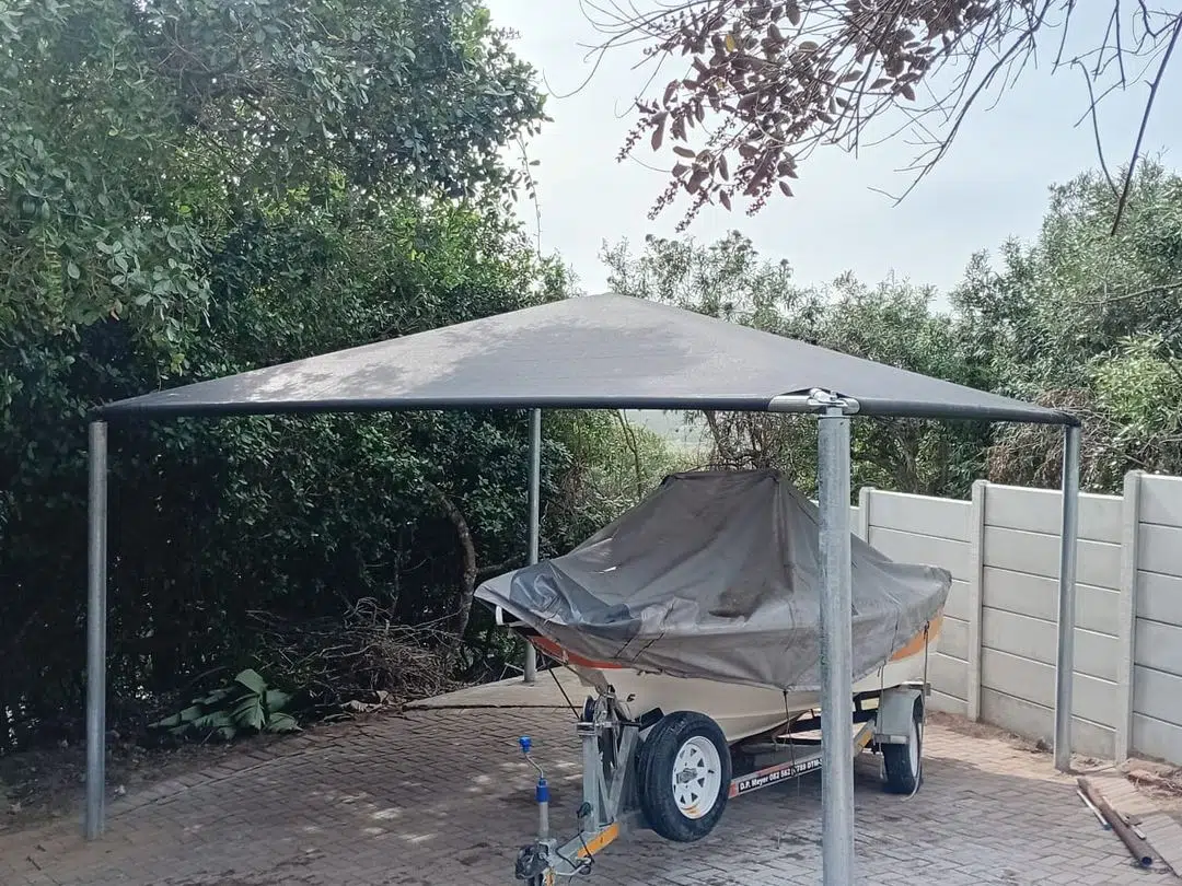 Shadeport in Wilderness with galvanised steel frame and charcoal shade cloth, covering a boat on trailer. Custom Blinds Garden Route installation, May 2026.