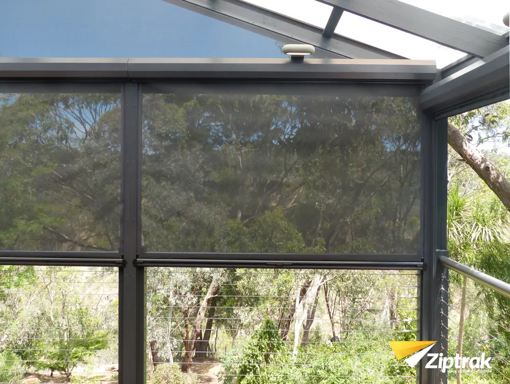 Ziptrak outdoor blinds on an elevated deck with bushland view, charcoal mesh fabric and aluminium track-guided system, supplied by Custom Blinds authorised Ziptrak retailer Garden Route