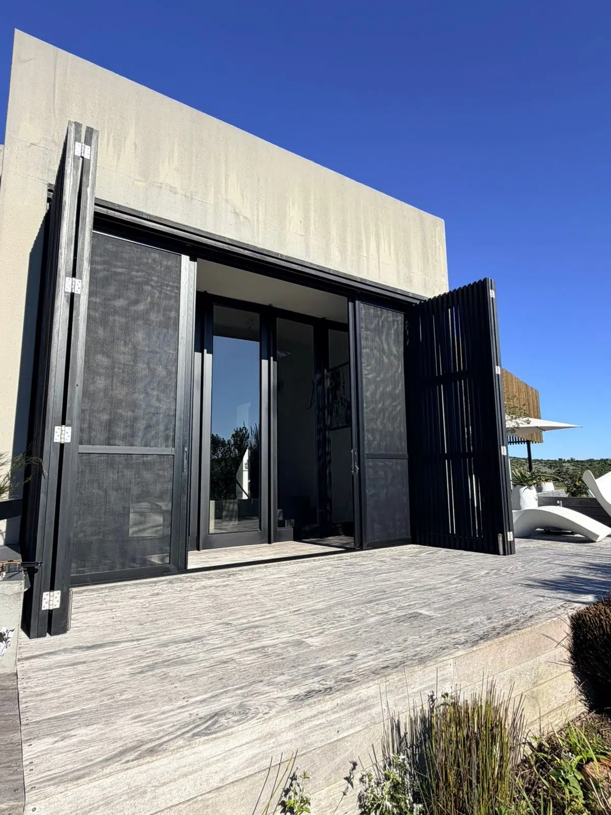 Folding slatted screen panels beside mesh screen doors, Pezula Private Estate