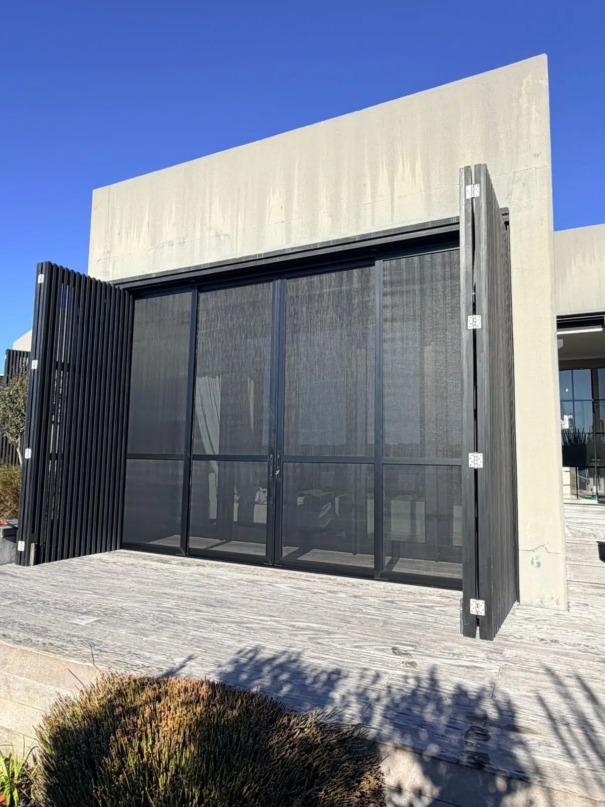 Black slatted security screen doors across a full height opening, Pezula Private Estate