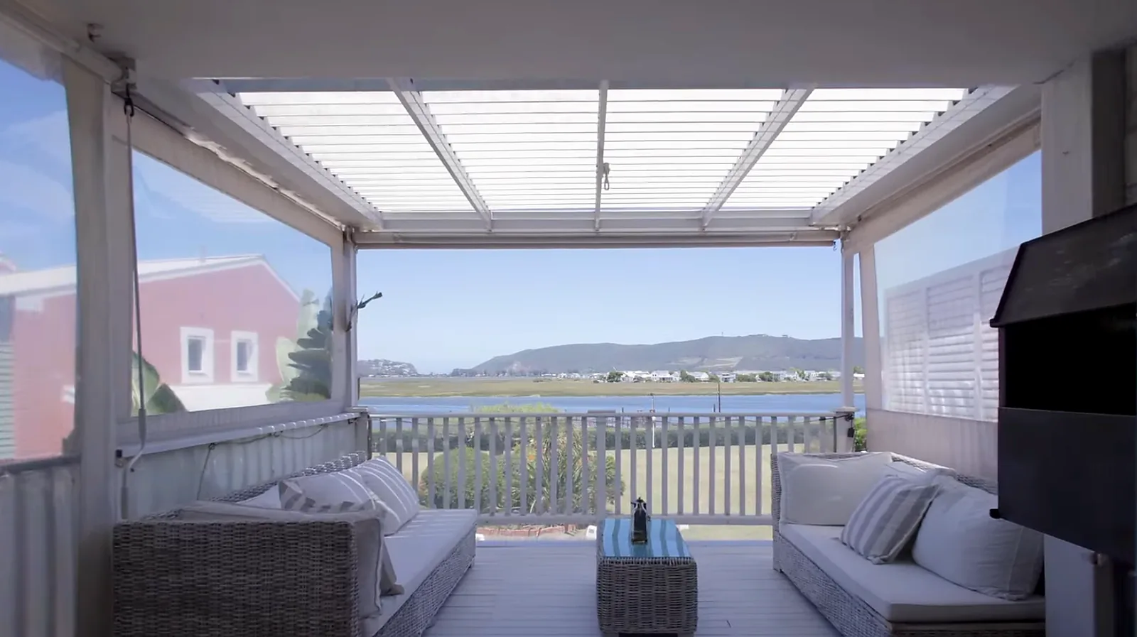 Louvred awning and outdoor blinds installed at Costa Sarda Knysna by Custom Blinds Shutters & Awnings, blades open over a lagoon-facing patio
