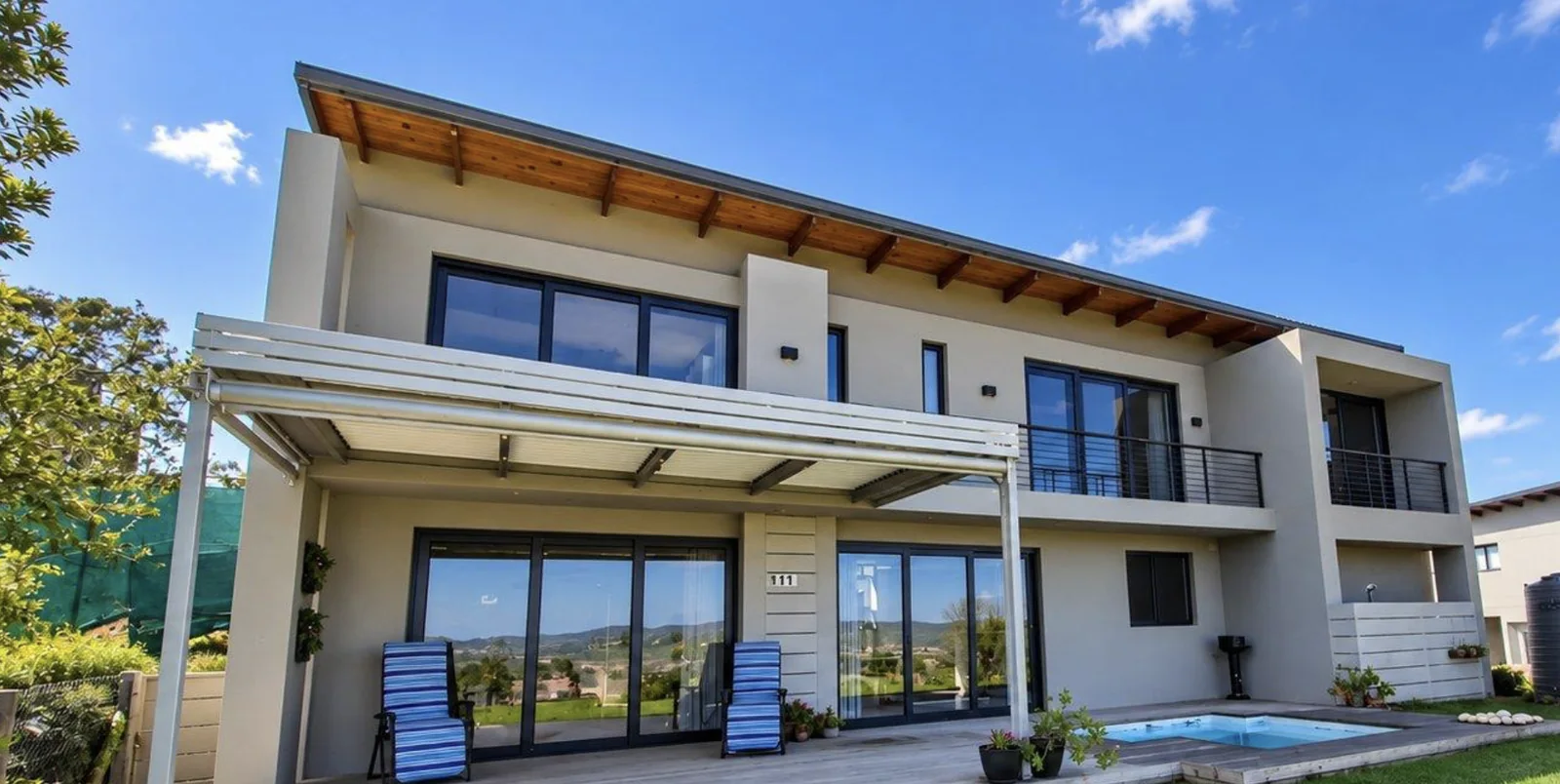 Aluminium louvred awning over a patio and pool deck at Simola Estate, Knysna, with outdoor blinds by Custom Blinds Shutters & Awnings